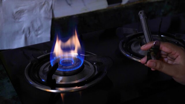 A women increase and decrease the gas blue flame on a kitchen stove. Cooking foods on gas flame concept.