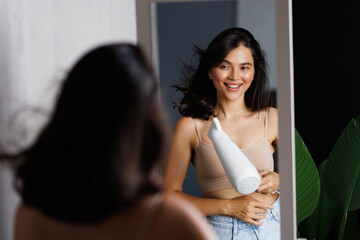 Fototapeta premium Beautiful woman using hair dryer near mirror at home