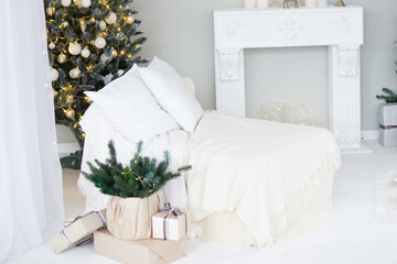 Bright interior with a false fireplace decorated for Christmas. Christmas trees with garlands, balloons and lights.