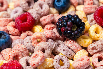Close up of colorful cereal rings mixed with fresh blackberries, raspberries, and blueberries, showing vibrant breakfast concept with sweet crunchy texture and natural fruit detail