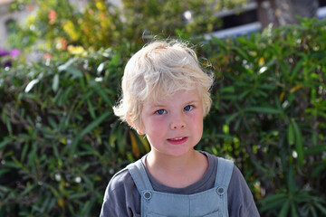 Smiling blond boy 4 years old portrait outdoors in summer greenery