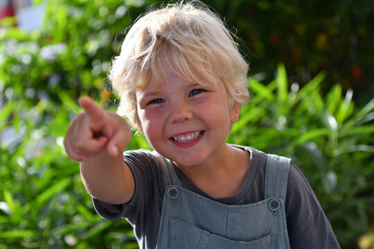Little Boy Pointing Outdoors with Green Nature Background