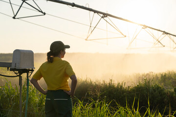 Farmer observing pivot irrigation system at sunset during drought