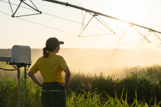 Farmer observing pivot irrigation system at sunset during drought