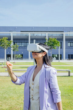 Businesswoman using VR headset outdoors in modern urban environment