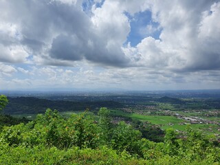 Obraz premium Lush green hills and cloudy horizon. Suitable for nature, travel, landscape, and environmental concepts. Perfect for backgrounds and marketing materials.