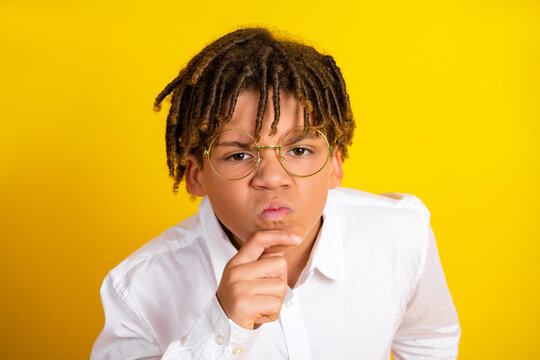 Curious young student in glasses contemplating ideas on a yellow background - Powered by Adobe