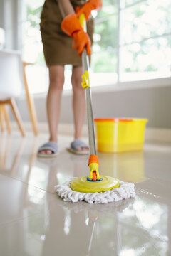 A woman mops the floor with a bucket nearby, representing housekeeping, hygiene, cleanliness, domestic chores, home care, sanitation, tidiness, professional cleaning service, household maintenance, an