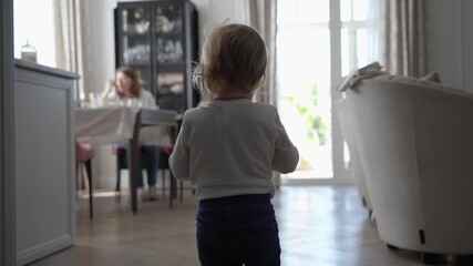 Child in bright, sunlit home engages with screen and observes peaceful family life and quiet domestic activities