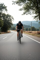 Naklejka premium Cyclist Riding on a Scenic Open Road Surrounded by Nature