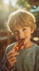 A cheerful child takes a bite of crispy bacon, surrounded by greenery and warm sunshine