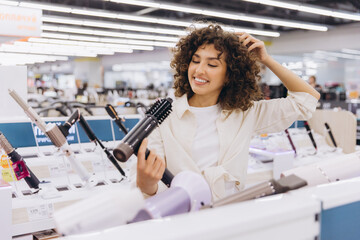 Woman choosing hairdryer in electronics store