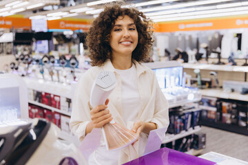 Woman Choosing Handheld Clothes Steamer in Electronics Store