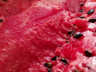 Juicy, close-up pulp of a ripe watermelon with black seeds looks incredibly appetizing. The bright red color and detailed texture create a sense of summer freshness and sweet taste.