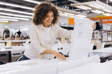 Woman choosing washing machine in appliance store