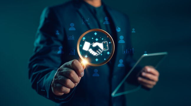 Businessman analyzing digital handshake icon with data and people graphics. Concept of partnership, customer relationship, networking, collaboration and business connection.