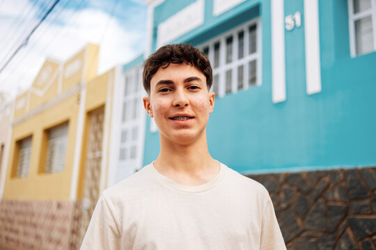Teenage boy with braces smiling outdoors in colorful urban neighborhood - Powered by Adobe