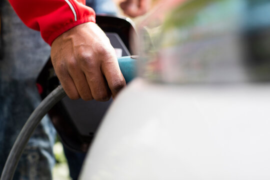 Hand in red sleeve plugging cable into electric car for charging. Germany