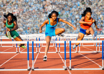 Three female athletes in colorful outfits jump hurdles on a red track in a stadium. USA