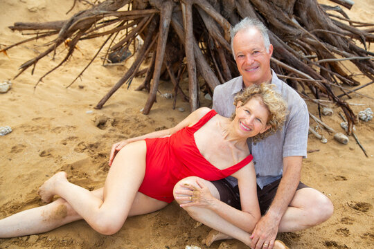 Elderly couple embracing on tropical beach with twisted trees in the background. Kepaniwai Park, Wailuku, Hawaii