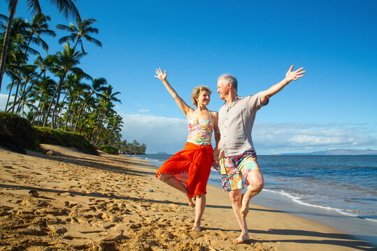 Senior couple joyfully posing in yoga stance on a sunny tropical beach. Kepaniwai Park, Wailuku, Hawaii