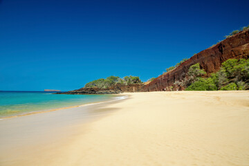 Pristine sandy beach with turquoise waters and rocky cliffs under a clear blue sky. Makena, Makena state park, Oneloa beach, Maui, Hawaii