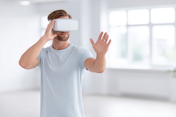 Young man wearing virtual reality headset is exploring immersive technology in a bright, modern indoor environment, showcasing innovative experiences