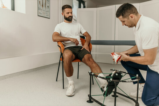 Podiatrist showing custom orthotics to patient in clinic