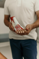 Doctor showing anatomical foot model to patient explaining muscle and bone structure