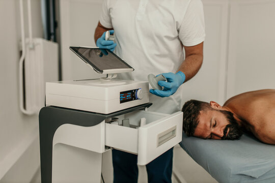 Doctor preparing equipment for shock wave therapy on patient's back