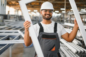 Operator of machine. Industrial worker indoors in factory. Young technician in white hard hat