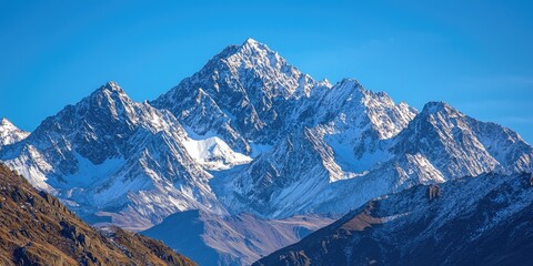Obraz premium rugged mountain peaks with snow-capped summits, the crisp air and clear sky emphasizing the grandeur of the landscape.