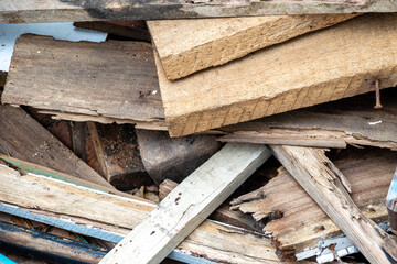 Construction waste after dismantling, a pile of wood stacked on a vacant lot for construction purposes, old wooden window and door frames.