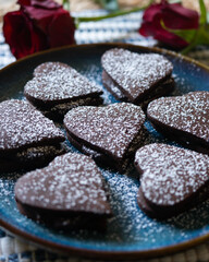 Heart-shaped dark chocolate cookies filled with chocolate and coffee cream. A recipe for lovers on Valentine's Day.