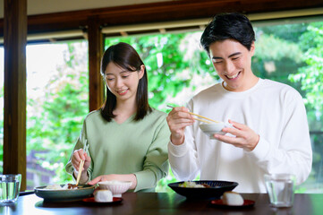 和風の家で並んで食事をする日本人男女