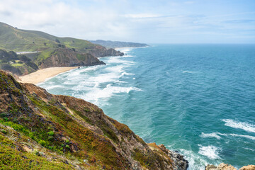 Dramatic ocean cliffs and lush coastal hills seen from Devils Bunker overlook, near Gray Whale Cove State Beach along Californias scenic Highway 1.