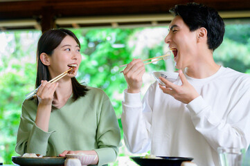 和風の家で並んで食事をする日本人男女