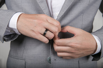 Obraz premium Man Fastening Suit Jacket, Close-Up on Hands with Ring