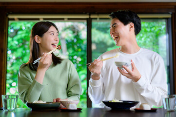 和風の家で並んで食事をする日本人男女