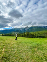 Fototapeta premium Young woman raising hands enjoying and admiring panoramic view of mountain valley of the High Tatras, Slovakia. Concept: relaxation, mindfulness, eco lifestyle. 