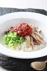 Close-up of oyster mushroom cheese gochujang bibimbap, a colorful Korean rice dish prepared with spicy sauce and fresh toppings by master chef Hanshunseop. Photographed in Korea.
