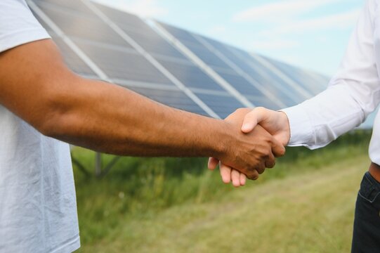 close up view of two male engineer handshake with solar panels background. business project deal and agreement in industrial of renewable and green energy concept - Powered by Adobe