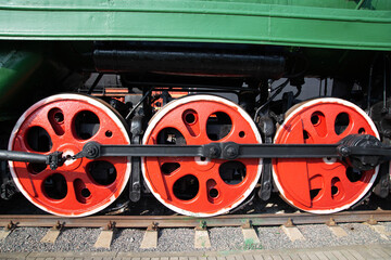 Naklejka premium Large metal wheels of a steam locomotive transmitting traction from the locomotive to the rails, industry, close-up