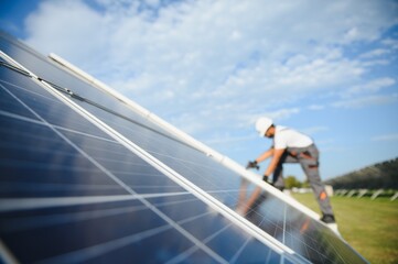 Indian man in uniform on solar farm. Competent energy engineer controlling work of photovoltaic cells