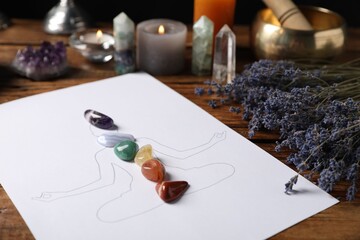 Human drawing with gemstones placed on chakras, lavender flowers on wooden table, closeup