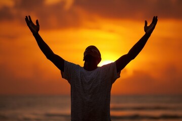Fototapeta premium Man Surrendering at Beach: Silhouette of Man with Raised Hands at Sunset