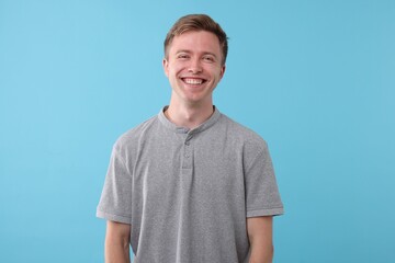 Handsome man laughing on light blue background. Positive emotion