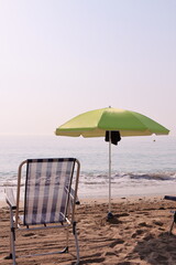 Green beach umbrella and chair by the sea