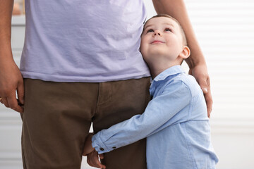 Little boy clinging to his father indoors. Separation anxiety