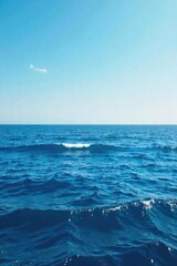 Fototapeta premium Vast expanse of deep blue ocean water meeting the horizon, waves gently rolling under a clear sky Perfect for travel, nature, and environmental themes , coastal, marine, beach
